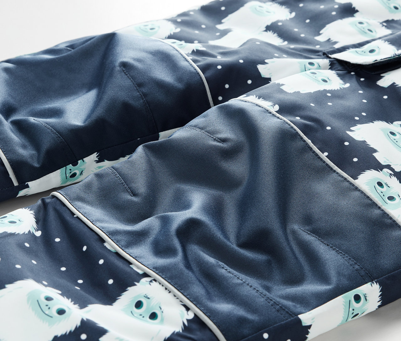 Detail modrých pyžamových nohavíc s bielymi snehuliakmi a bielymi bodkami.