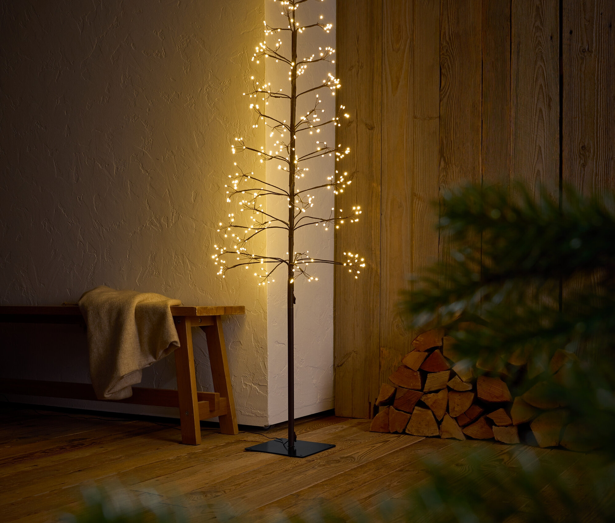 Dekoratívny strom s vetvami a LED svetlami stojí v interiéri.