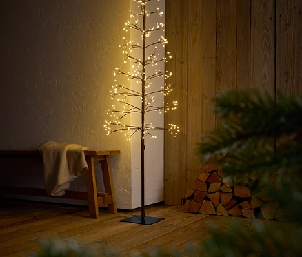 Dekoratívny strom s vetvami a LED svetlami stojí v interiéri.