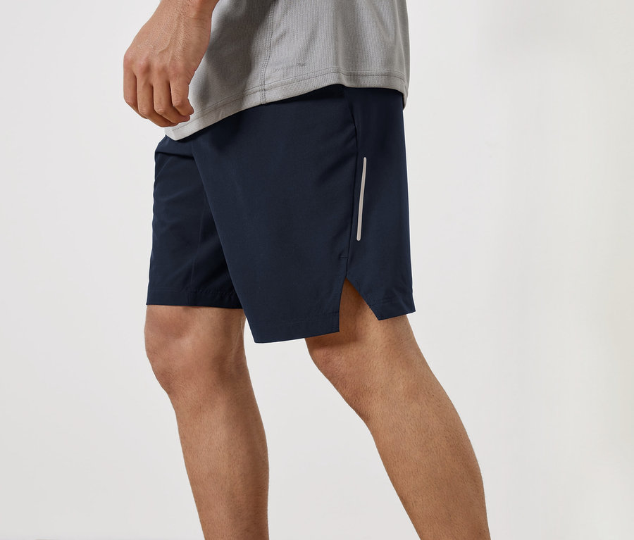 Muž má na sebe tmavomodré šortky a sivé tričko.