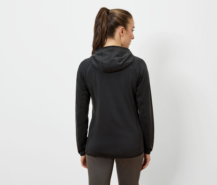 Žena chrbtom k fotoaparátu má na sebe čiernu bundu s kapucňou a tmavé nohavice.