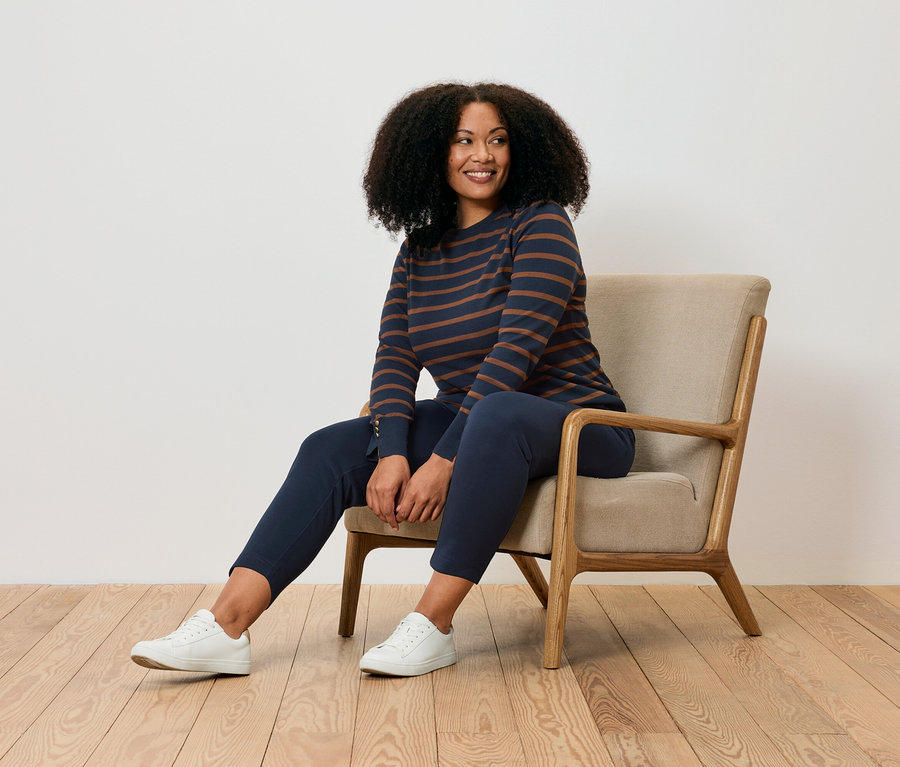 Žena sedí v kresle a má na sebe joggpant.