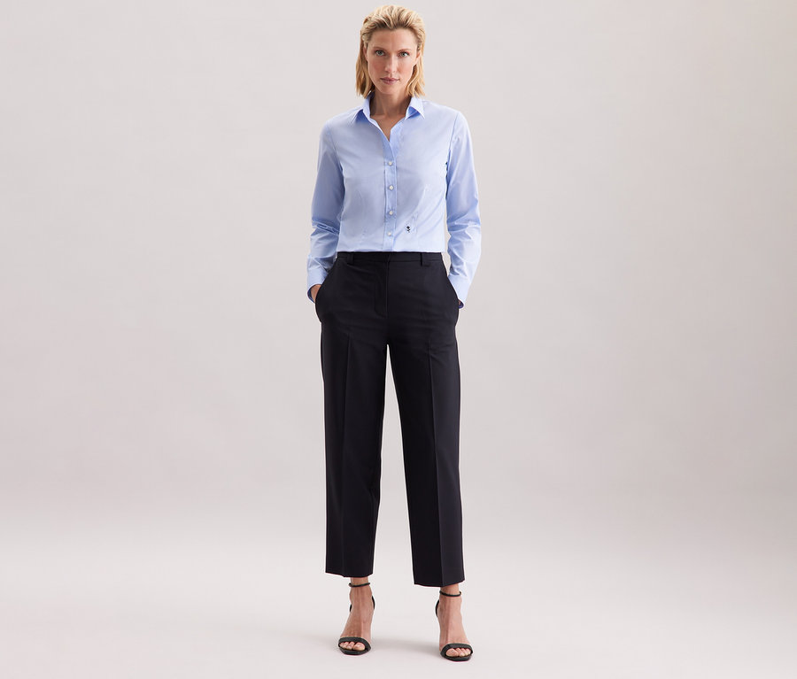 Žena v svetlomodrej blúzke Seidensticker Slim Fit non iron a tmavých nohaviciach.