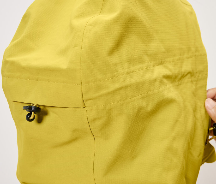 Detail žltej bundy s kapucňou a sťahovacou šnúrkou.