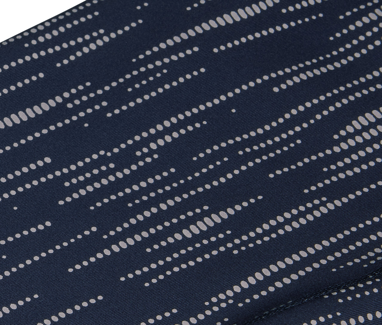 Detailný záber na tmavomodrú látku s motívom rovnobežných bielych bodiek.