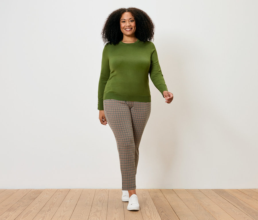 Žena kráča a má na sebe svetlozelený sveter z jemného úpletu.