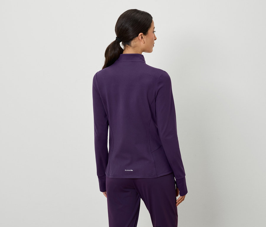 Pohľad zozadu na ženu s hnedými vlasmi stiahnutými do copu, oblečenú do fialovej bundy a nohavíc.