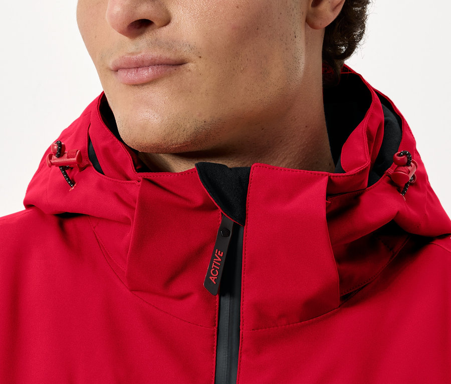 Muž má na sebe červenú bundu s kapucňou.