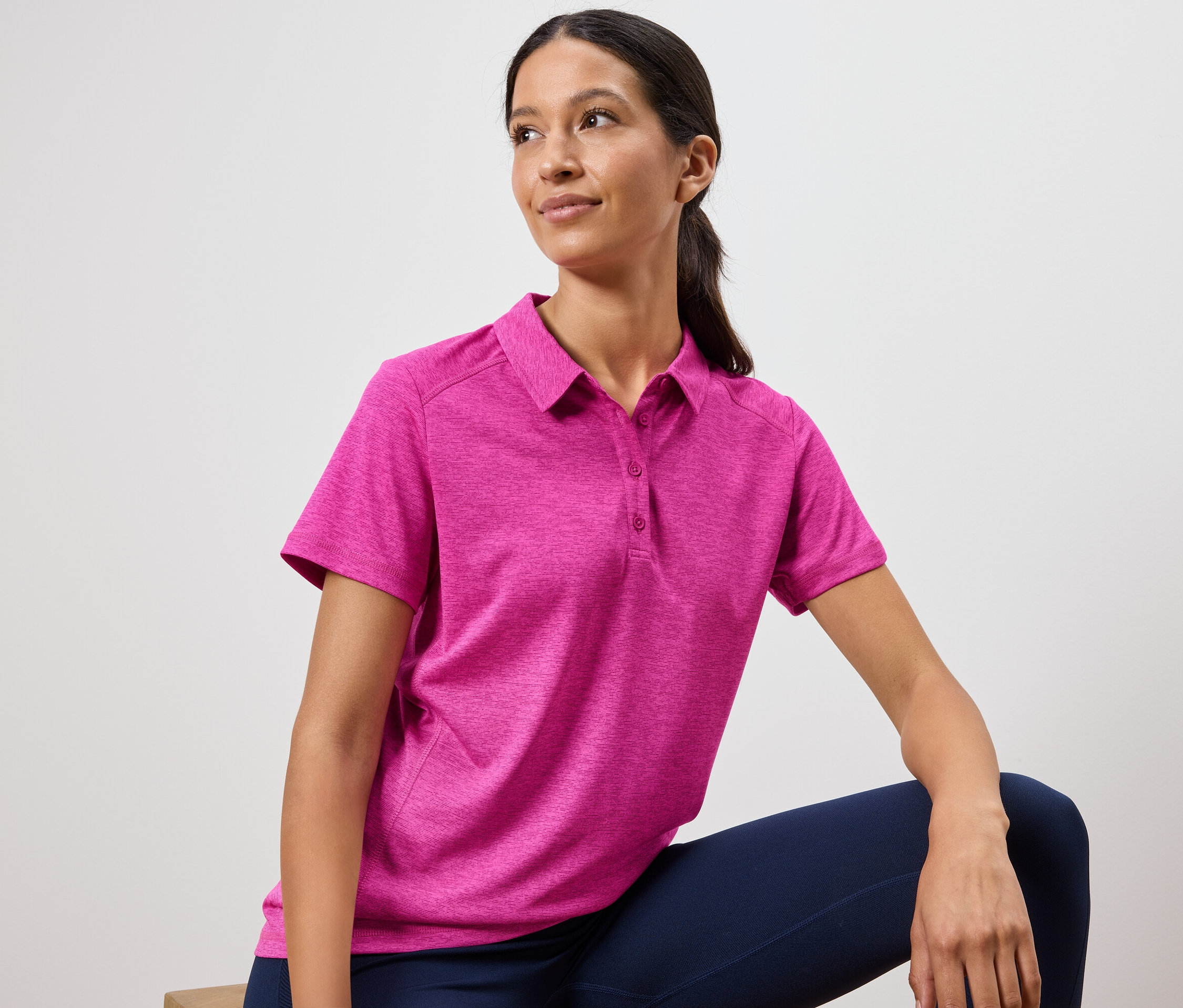 Žena má na sebe ružové polotričko a tmavomodré legíny.