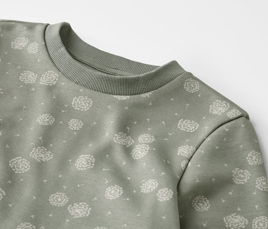 Detail zelenej teplákovej súpravy s potlačou púpav.