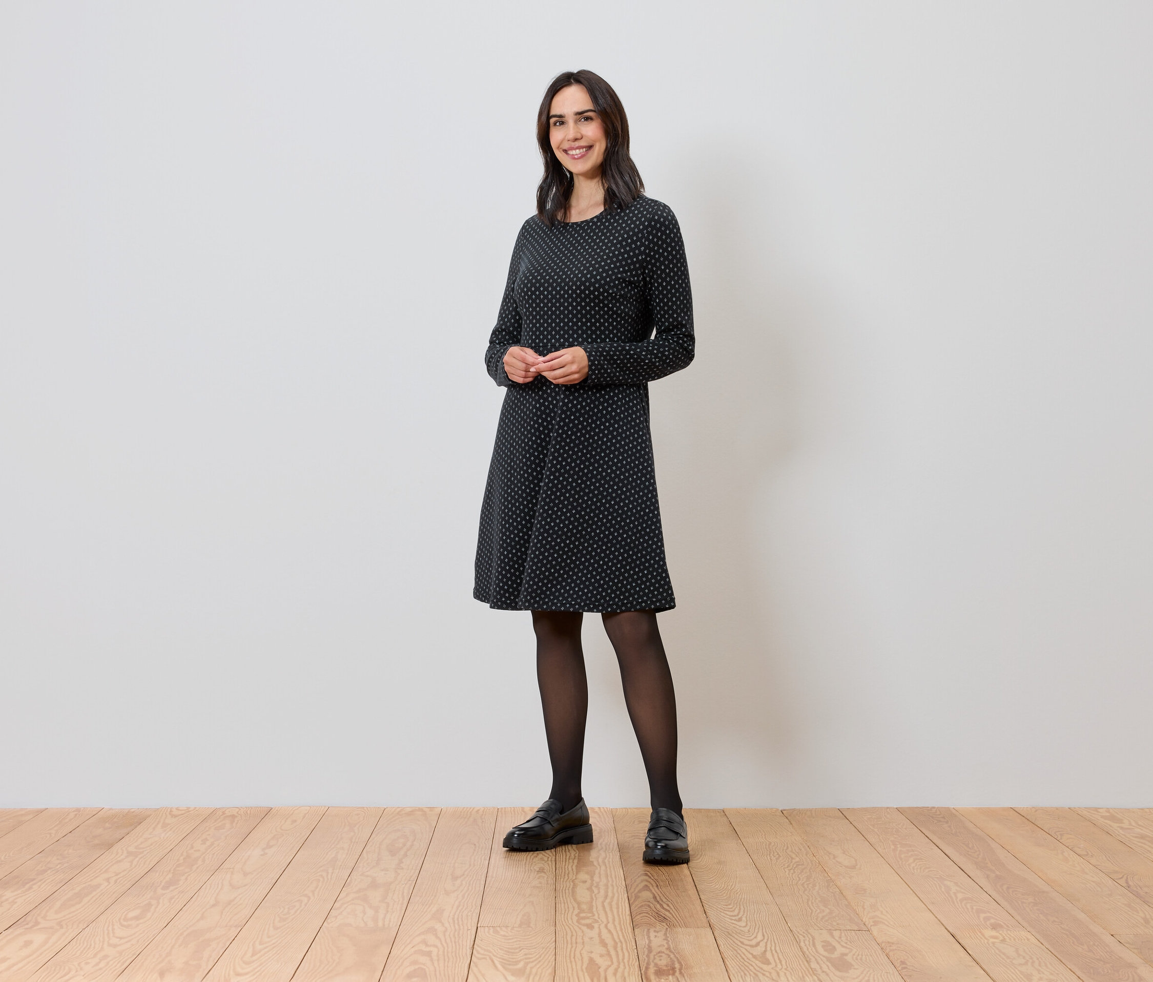 Žena stojí a má na sebe trblietavé žakárové šaty.