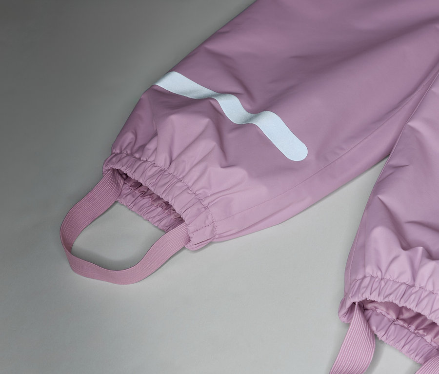 Detail ružových nepremokavých nohavíc s elastickými popruhmi a reflexnými pruhmi na nohách.