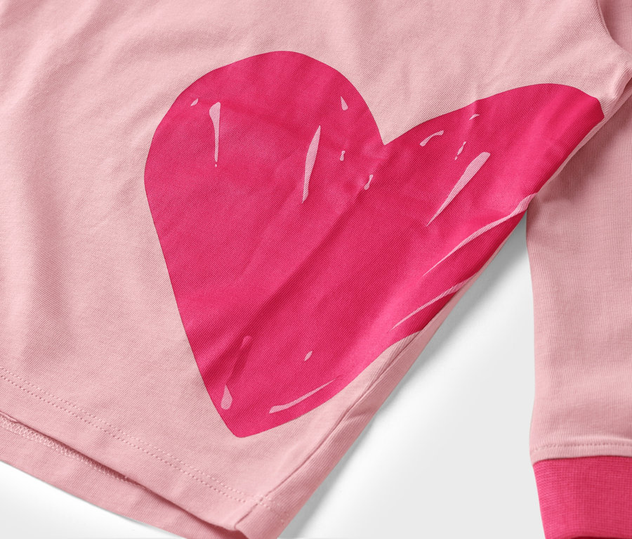 Detail ružovej látky s veľkou, ružovou potlačou srdca.