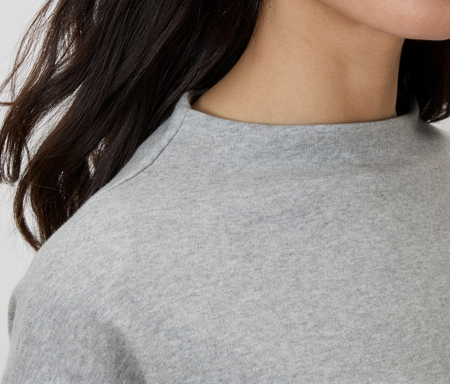 Detailný záber ženy v šedom tope s rolákom.