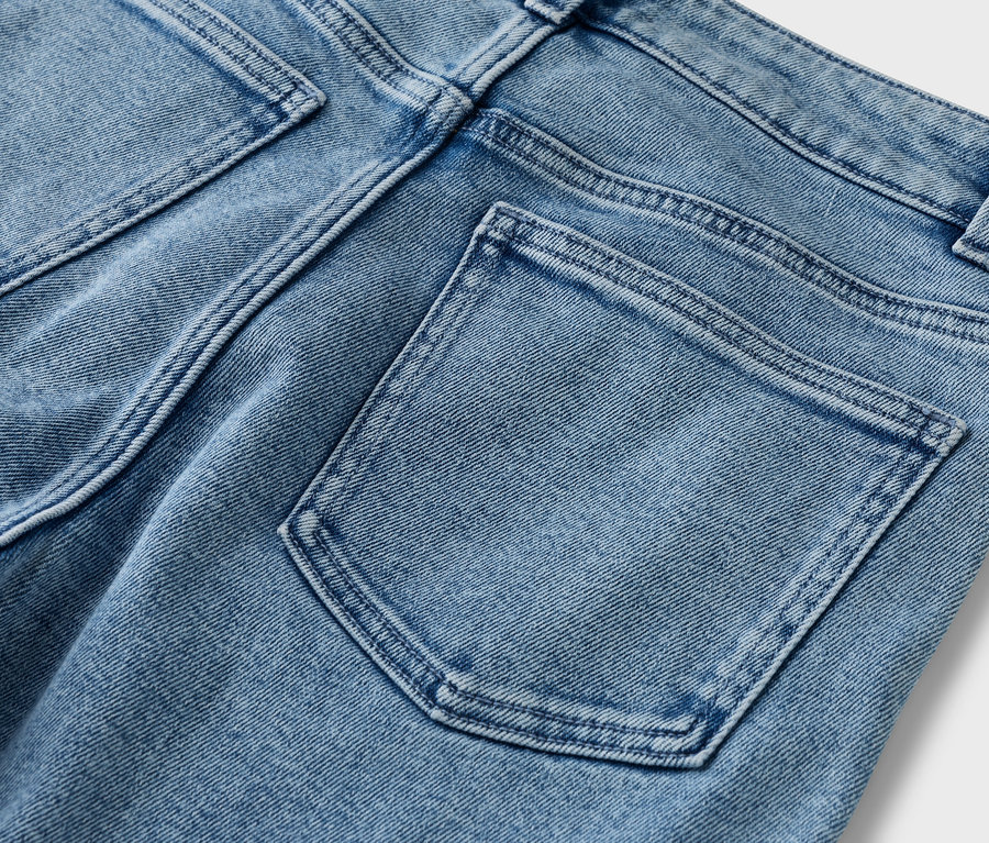 Detailný pohľad na zadnú časť svetlomodrých džínsov s vreckami na zadku.