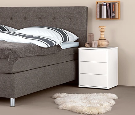 Boxspringová posteľ s nočným stolíkom typu boxspring a dekoráciami.