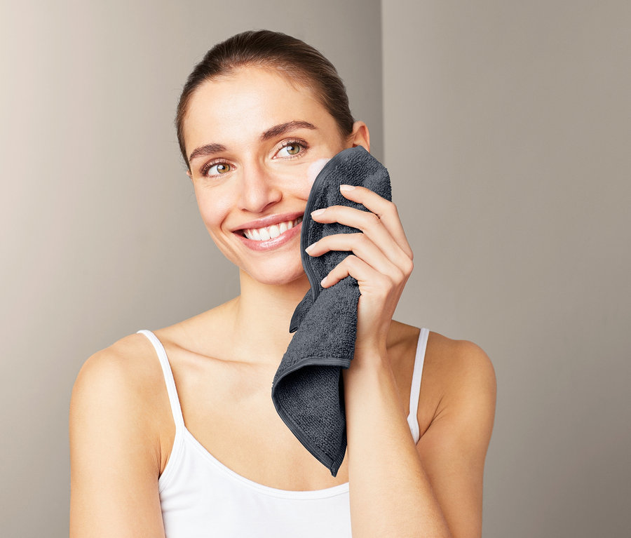 Žena si utiera tvár sivou kozmetickou utierkou z mikrovlákna, 3 ks.