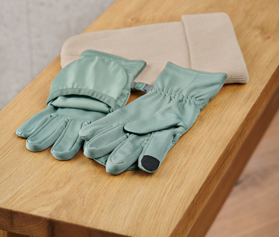 Dvoje odklápacie bežecké rukavice ležia na drevenej lavici.