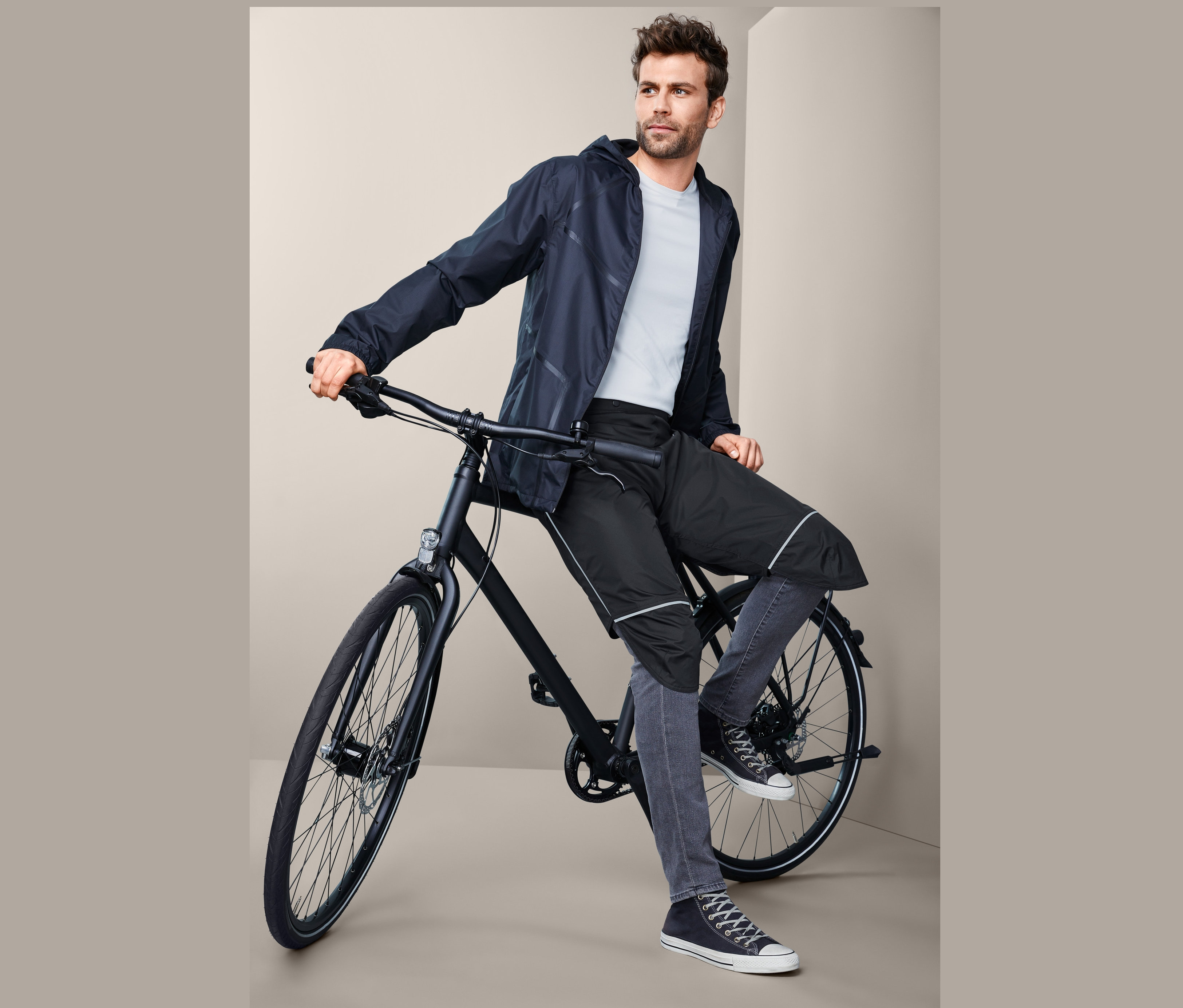 Muž sedí na bicykli a má na sebe krátke nohavice do dažďa, unisex.