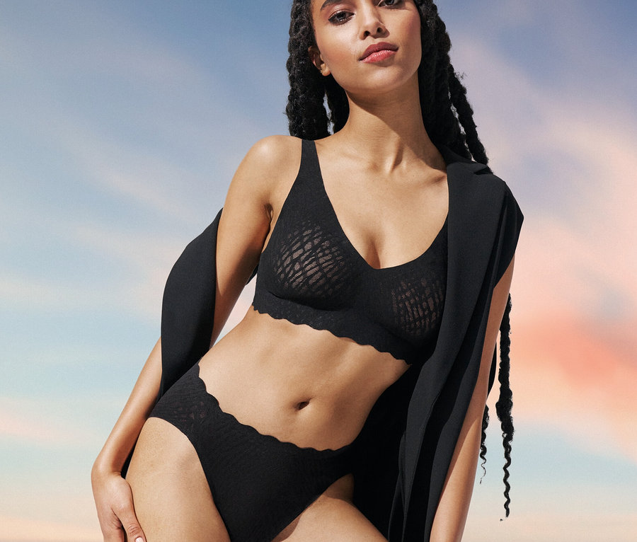 Žena pózuje v čiernej podprsenke sloggi ZERO Feel Bliss Soft bra a nohavičkách sloggi ZERO Feel Bliss High leg.