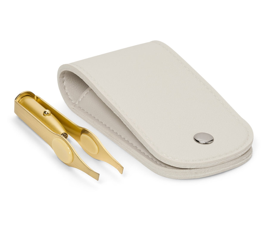 Zlatá pinzeta leží vedľa otvoreného bieleho puzdra.