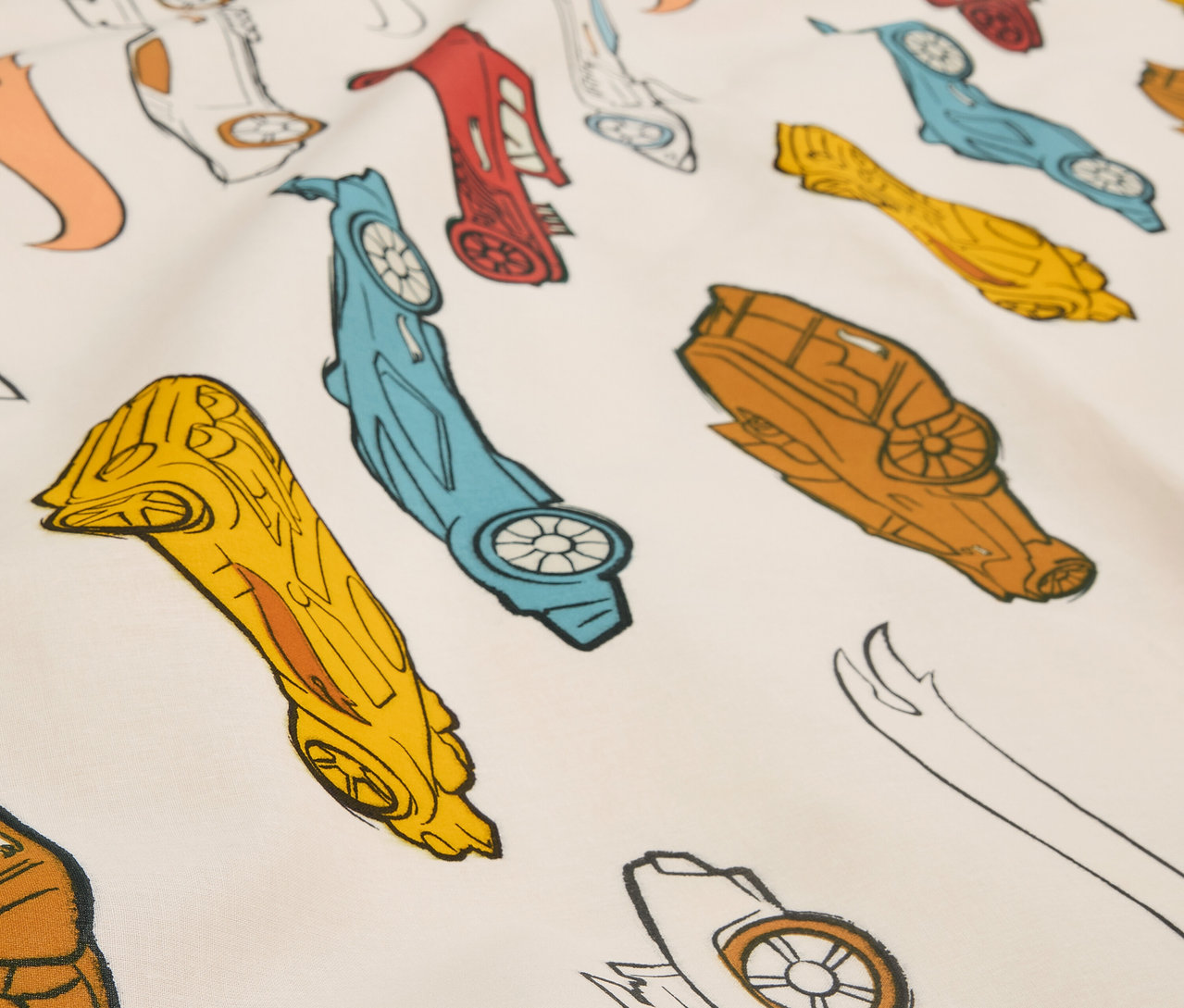 Detailný záber na látku s potlačou štylizovaných pretekárskych autíčok v rôznych farbách.