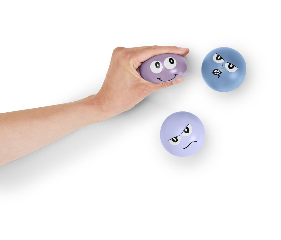 Ruka drží fialovú loptičku s tvárou. Ďalšie dve loptičky s tvárou ležia na bielom pozadí.
