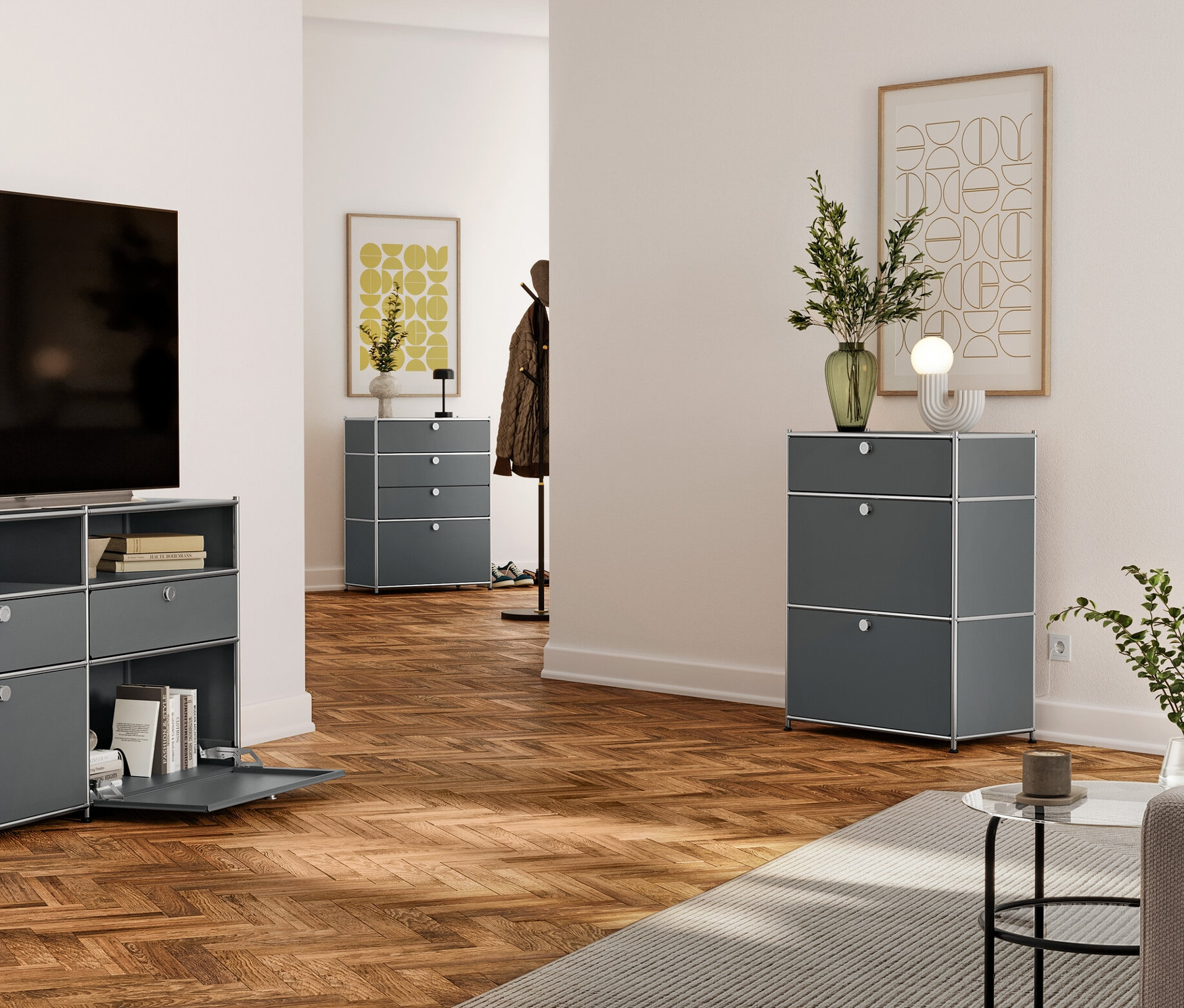 Obývacia izba s televízorom na šedej kovovej komode so zásuvkami a otvorenými policami. V pozadí šedá komoda s tromi zásuvkami a ďalšia v chodbe.