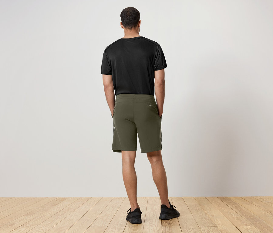 Muž chrbtom k fotoaparátu má na sebe čierne tričko a zelené šortky.