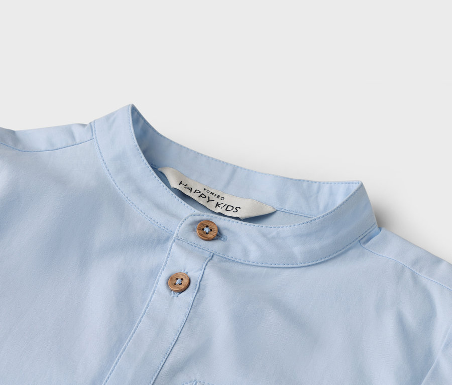 Detailný záber na svetlomodrú košeľu s dvoma gombíkmi a golierom.