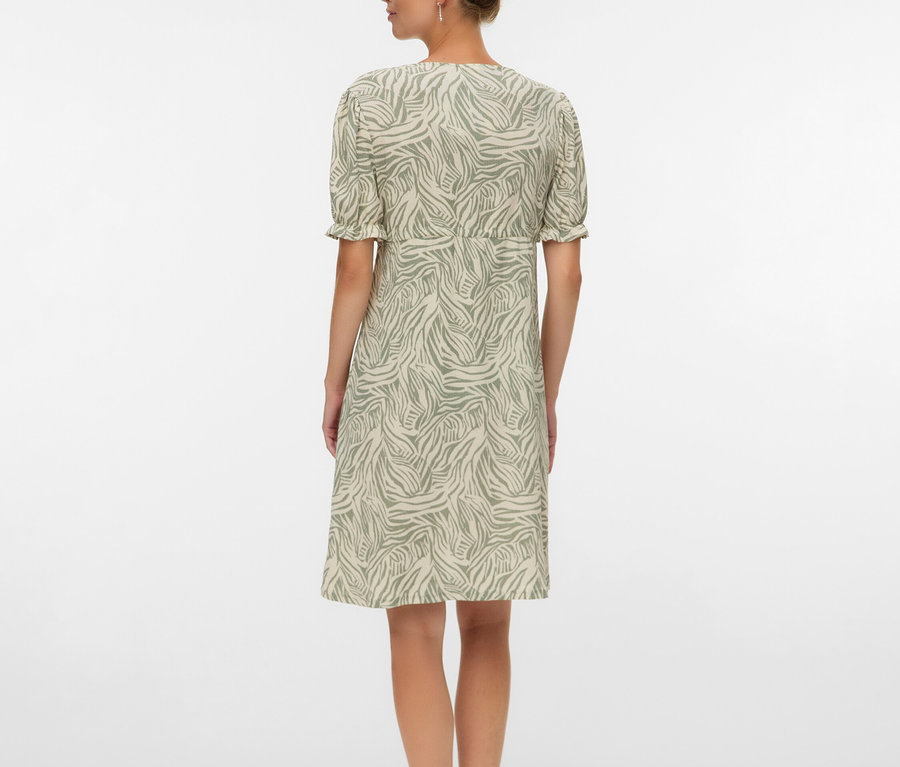 Žena zozadu v šatách po kolená so vzorom zebry a sandáloch.