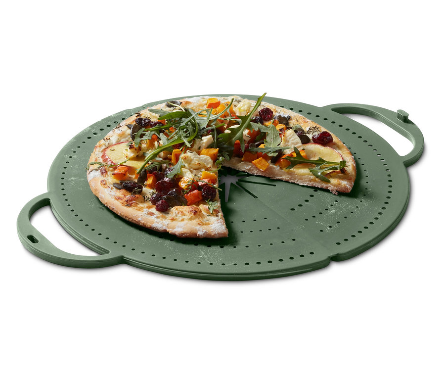 Pizza so zeleninovou oblohou leží na zelenom plechu na pizzu.
