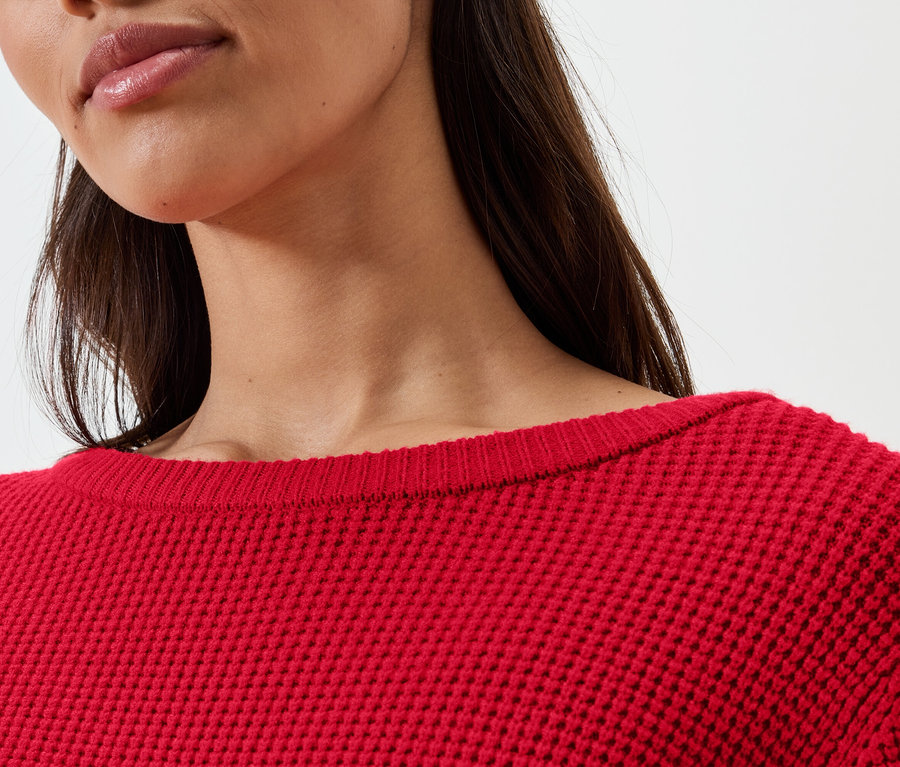 Detail ženy v červenom svetri.