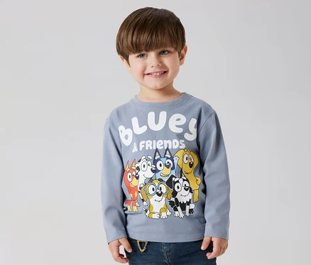 Usmievavý chlapec má na sebe detské tričko s dlhým rukávom NAME IT »BLUEY« s motívom Bluey a priateľov.