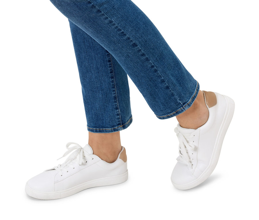 Nohy osoby v modrých džínsoch a bielych teniskách.