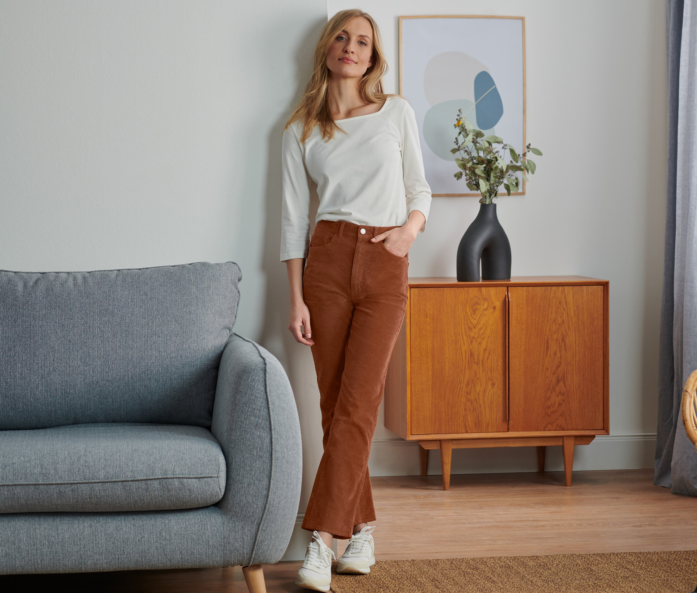 Žena pózuje v menčestrových nohaviciach a bielom tope.