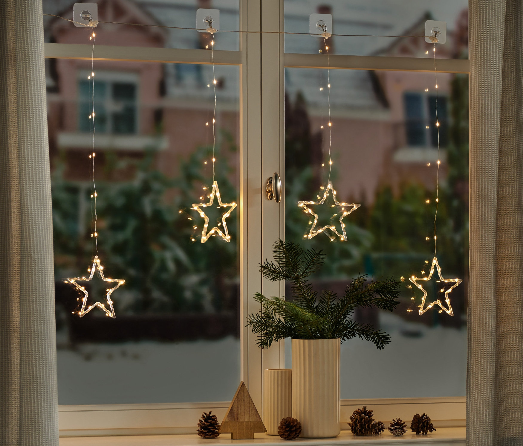 Štyri LED svetelné závesy s hviezdami visia v okne.