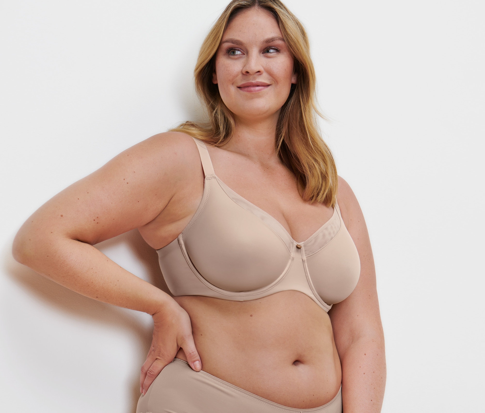 Žena pózuje v béžovej zmenšujúcej podprsenke.