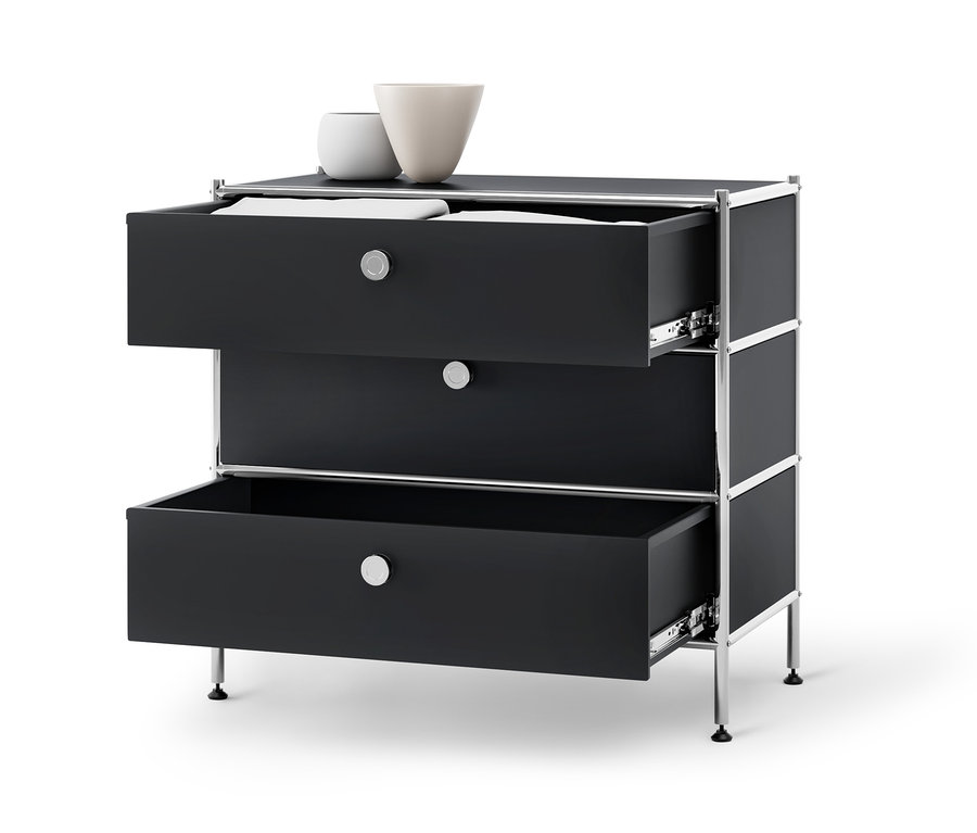Čierna kovová komoda »CN3« s 3 zásuvkami, z ktorých dve sú otvorené a na hornej strane sú dve vázy.