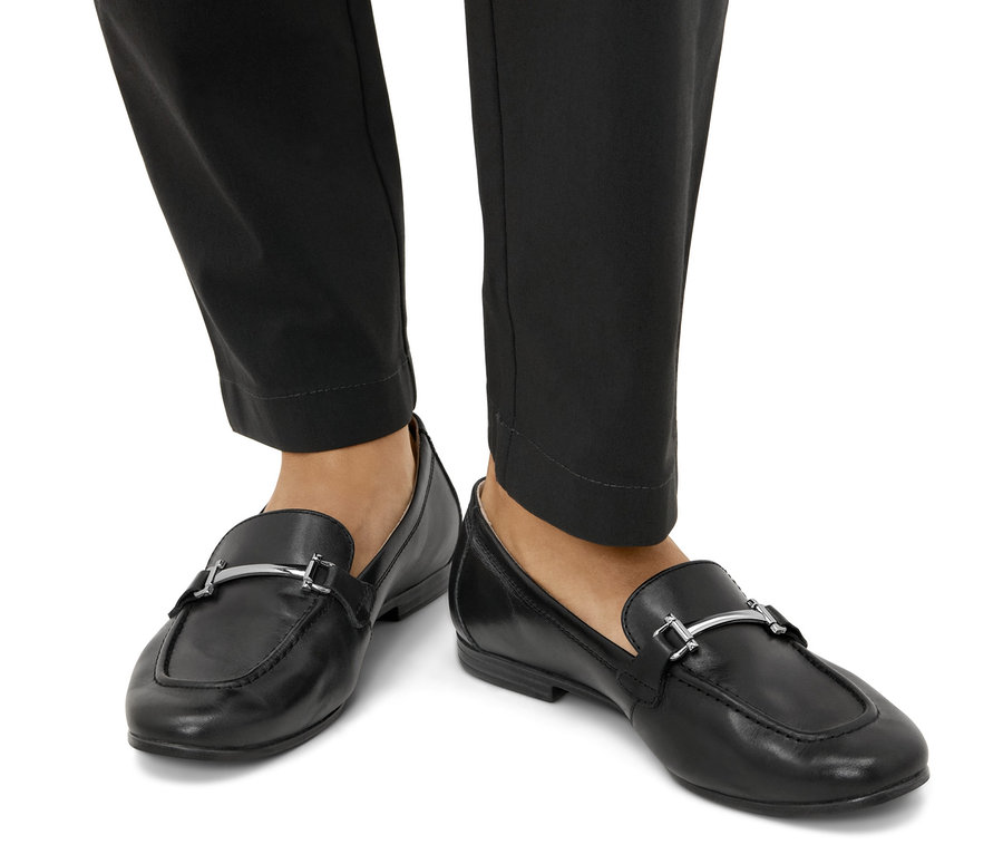 Nohy v čiernych kožených mokasínach.