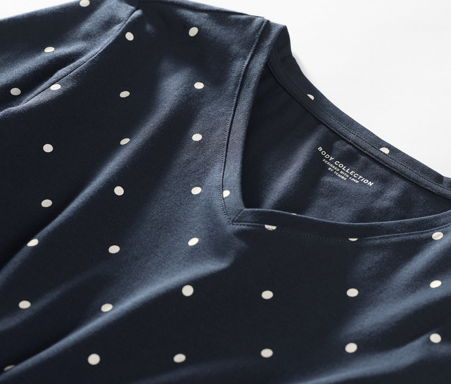 Detail nočnej košele s tmavomodrým pozadím a bielymi bodkami.