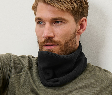 Muž s hnedými vlasmi sedí a má na sebe čierny flaušový nákrčník.