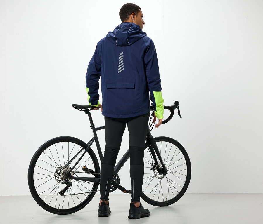 Muž v bunde s kapucňou stojí vedľa bicykla.
