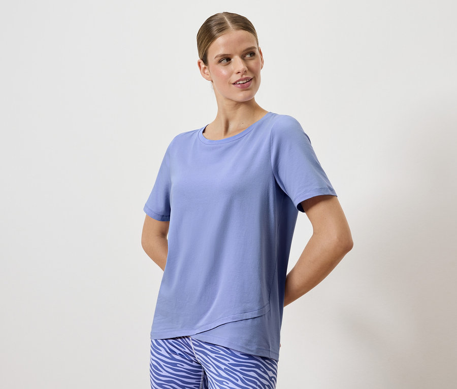 Žena pózuje v modrom tričku a nohaviciach so zvieracím vzorom.