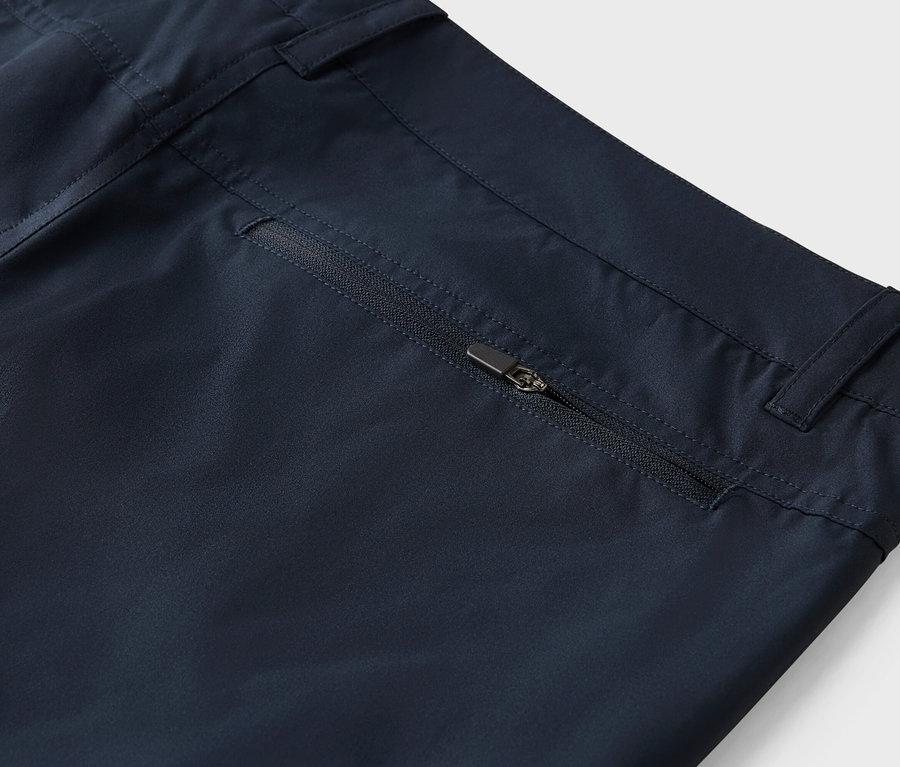 Detailný záber na námornícke modré nohavice s vreckom na zips.