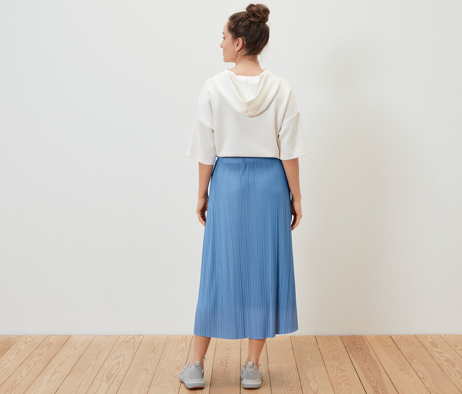 Žena má na sebe plisovanú sukňu.