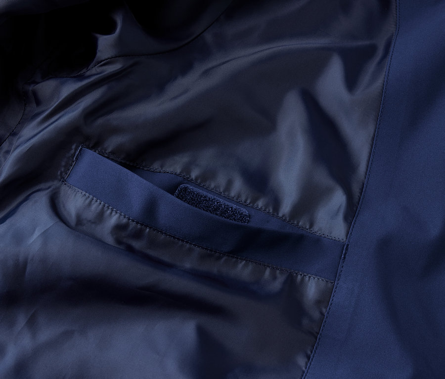 Detail modrej funkčnej outdoorovej bundy s vnútorným vreckom.