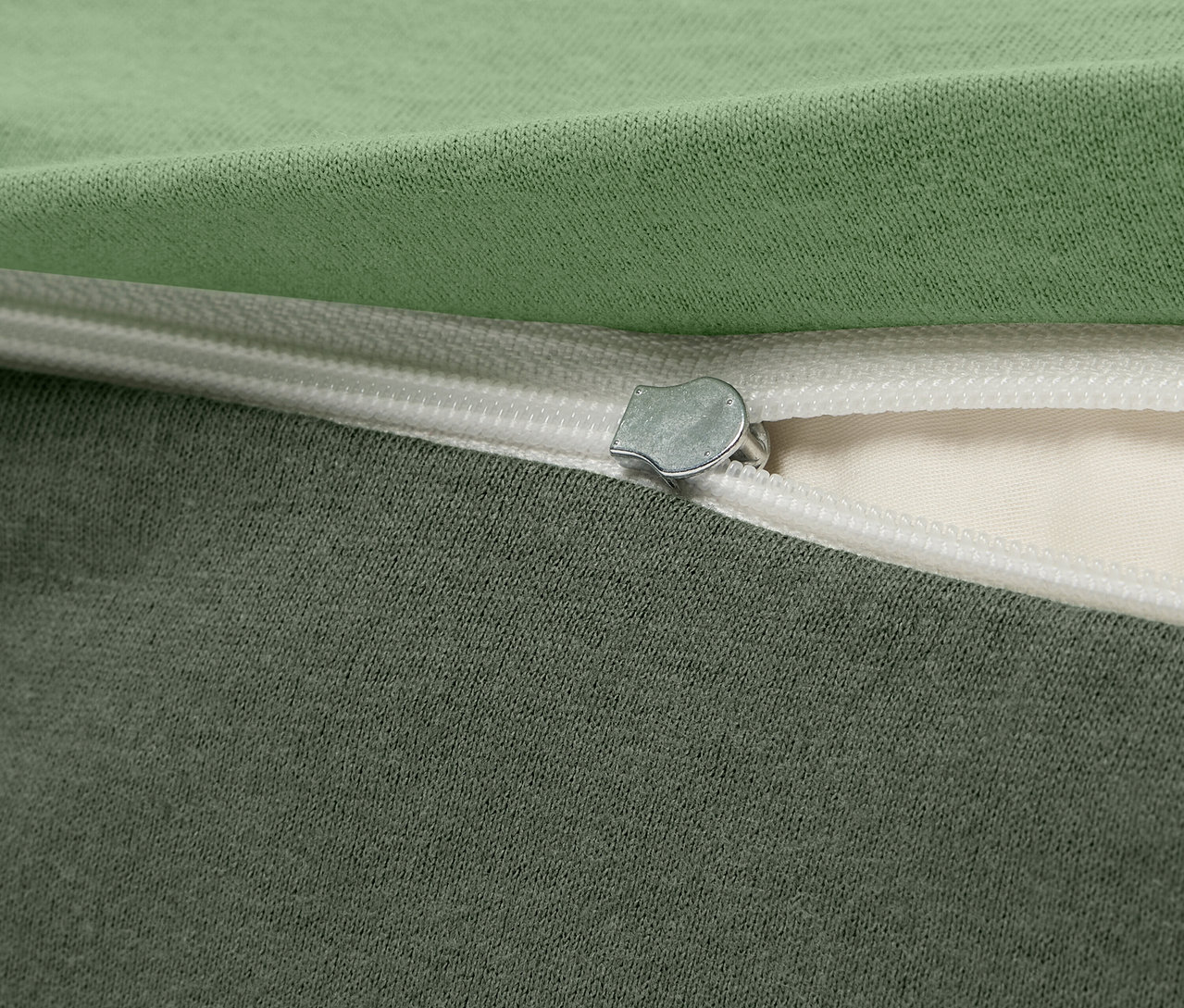 Detail zeleného a sivého látkového obalu so zipsom.