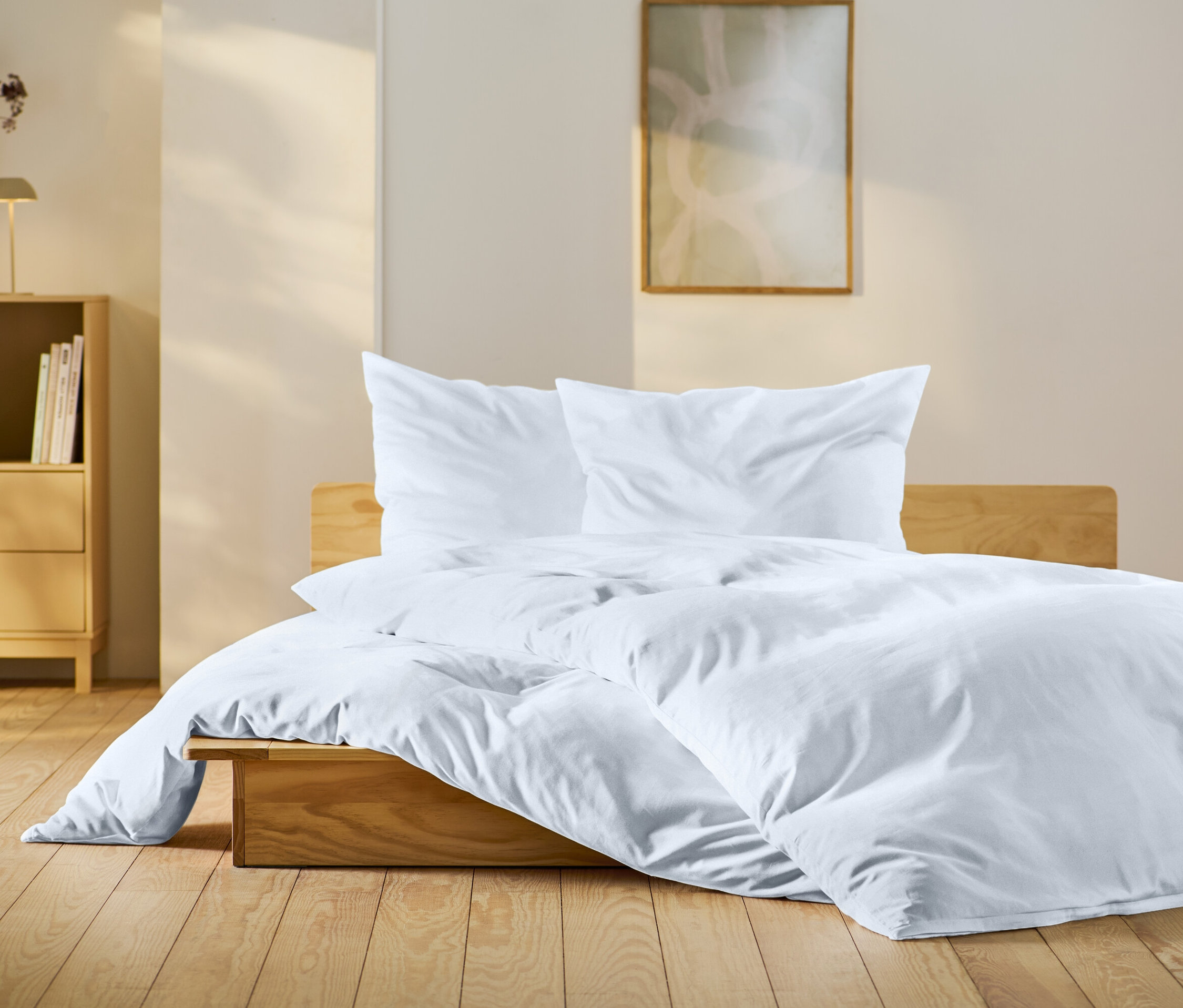 Spálňa s drevenou posteľou s bielymi obliečkami, dreveným nočným stolíkom a dekoráciami.