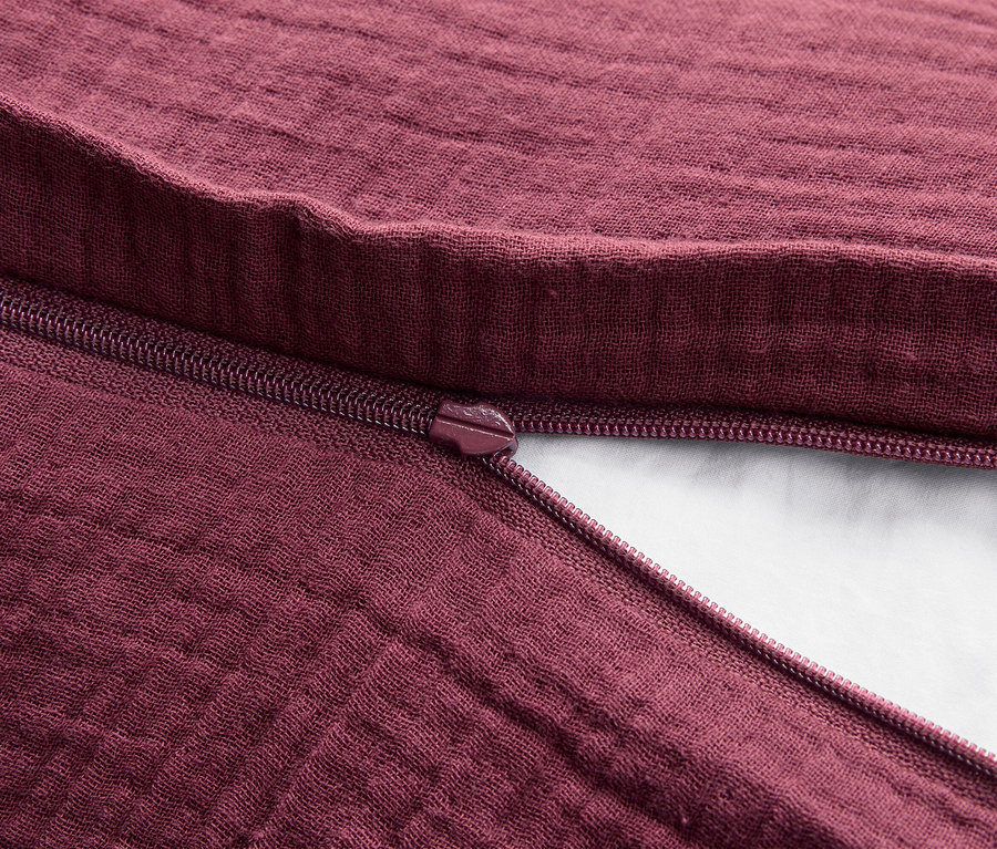 Detail bordovej látkovej textílie s rozopnutým zipsom.